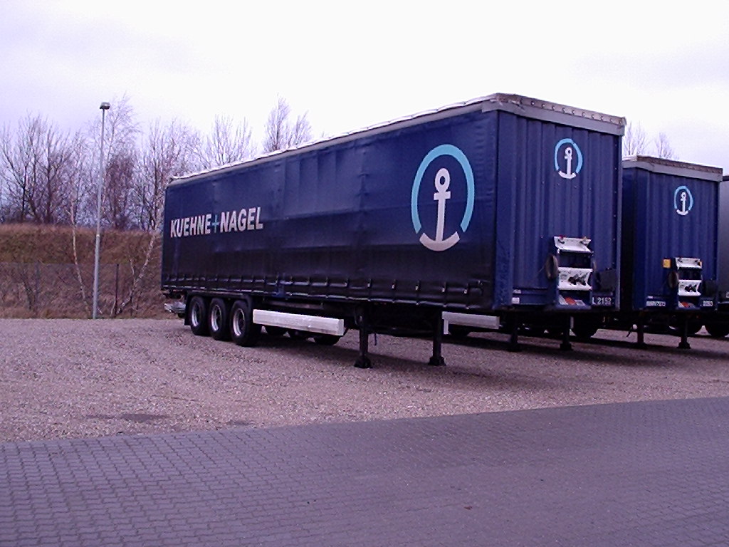 Remorques de fret bâchées stationnées sur une plateforme logistique.